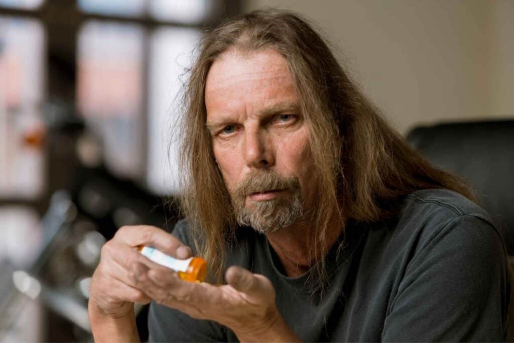 Fentanyl Detox In Ohio 1 Man holding a prescription bottle while experiencing distress associated with opioid withdrawal and fentanyl dependence.