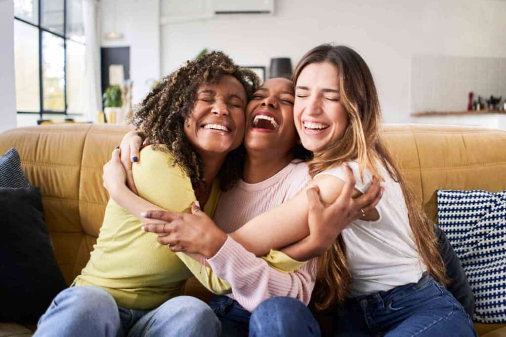 Three women embracing and smiling together, representing hope, emotional support, and recovery after seeking addiction treatment.