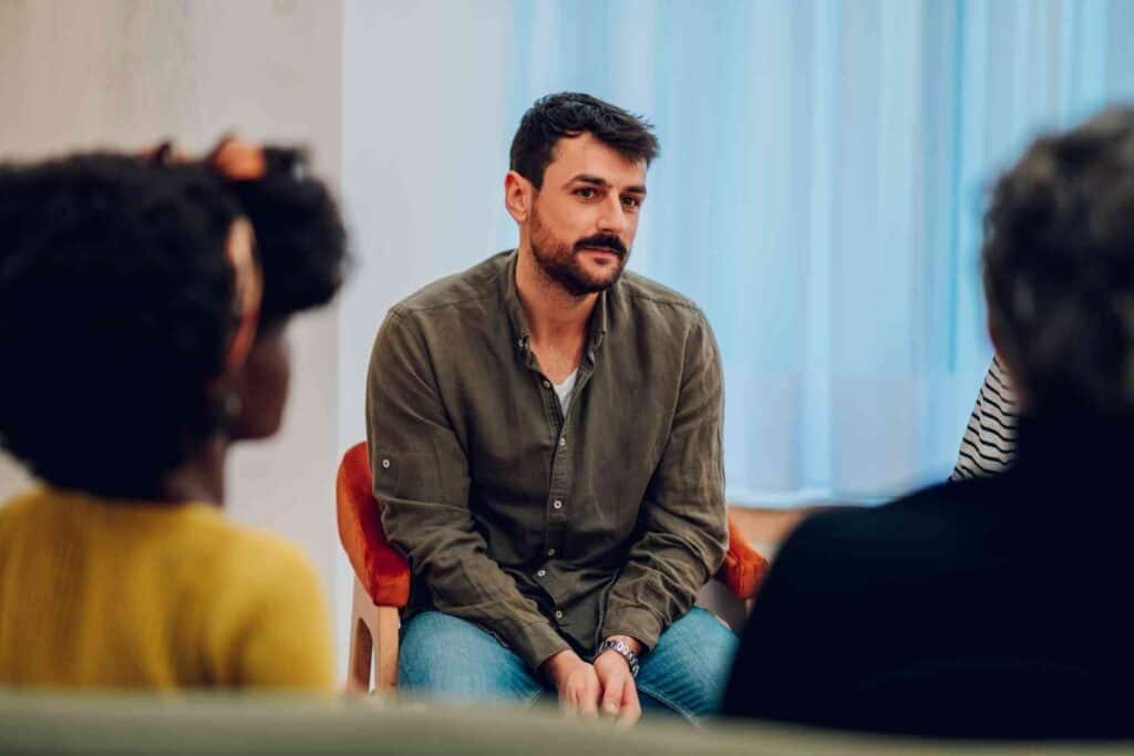 Man listening during a group therapy session in drug and alcohol rehab