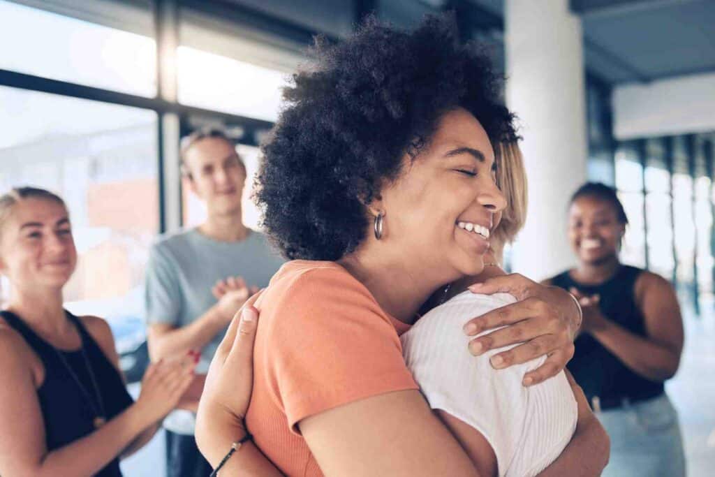 Person hugging another during a supportive group session in addiction recovery