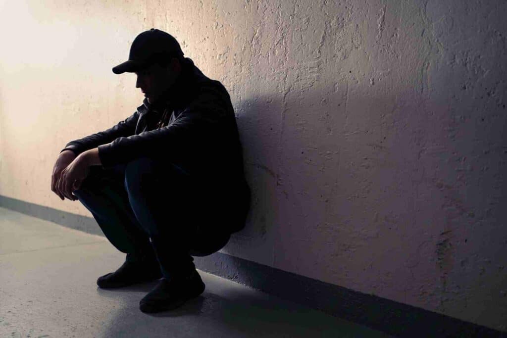 Person sitting alone against a wall, illustrating the isolation and emotional challenges associated with substance addiction.