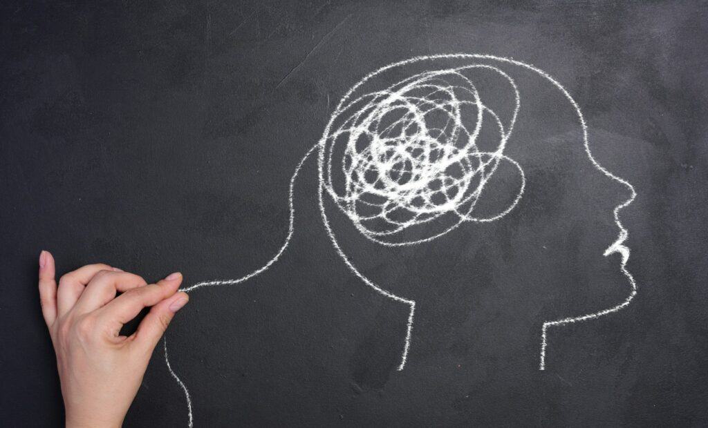 Profile of a human head with a tangled spiral in the brain area. The head is drawn in white chalk.