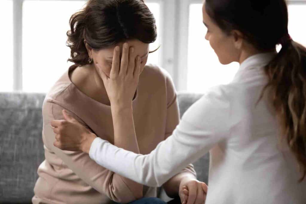 A woman comforting a loved one who appears emotionally distressed while discussing addiction recovery and treatment options.