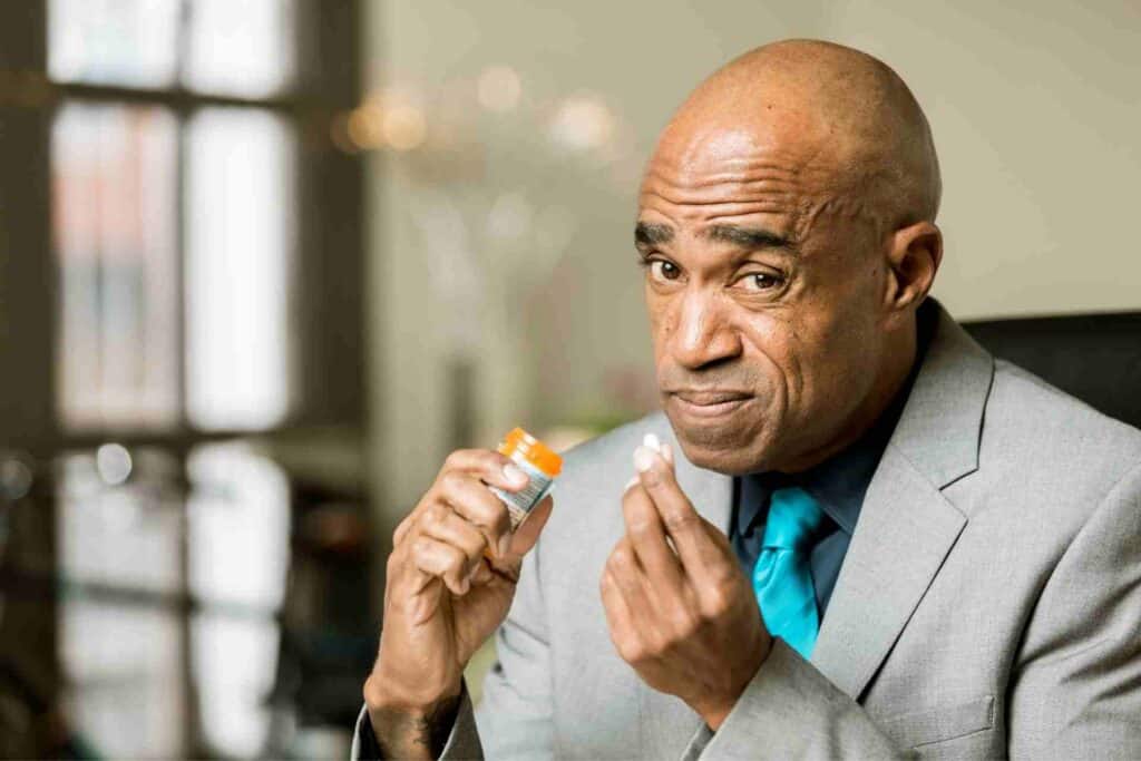 Man holding a prescription pill and medication bottle before taking a prescribed dose