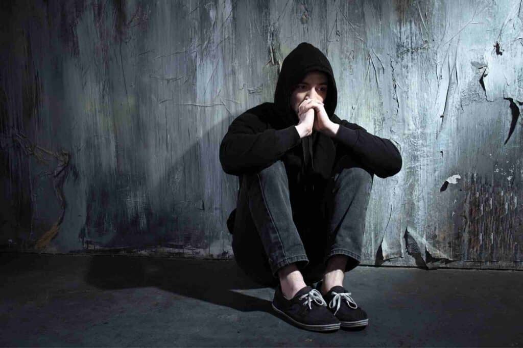 Man sitting alone in a hoodie, reflecting the emotional isolation and mental health challenges associated with substance addiction.