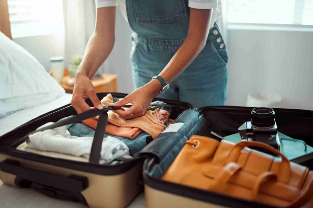 Person packing clothes and personal belongings into a suitcase before leaving for an inpatient rehab program.